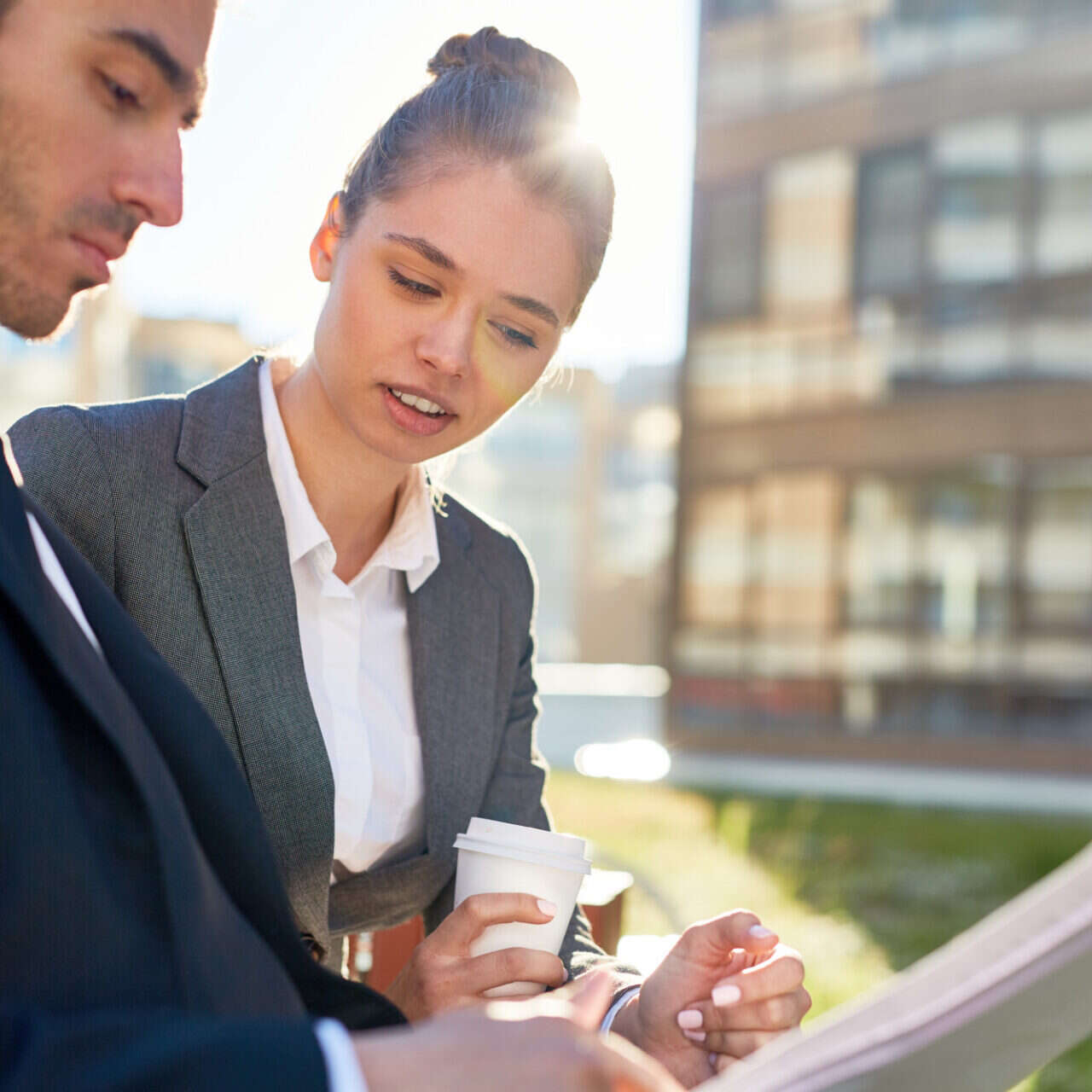 Two business professionals reviewing lease documents outside a commercial office building