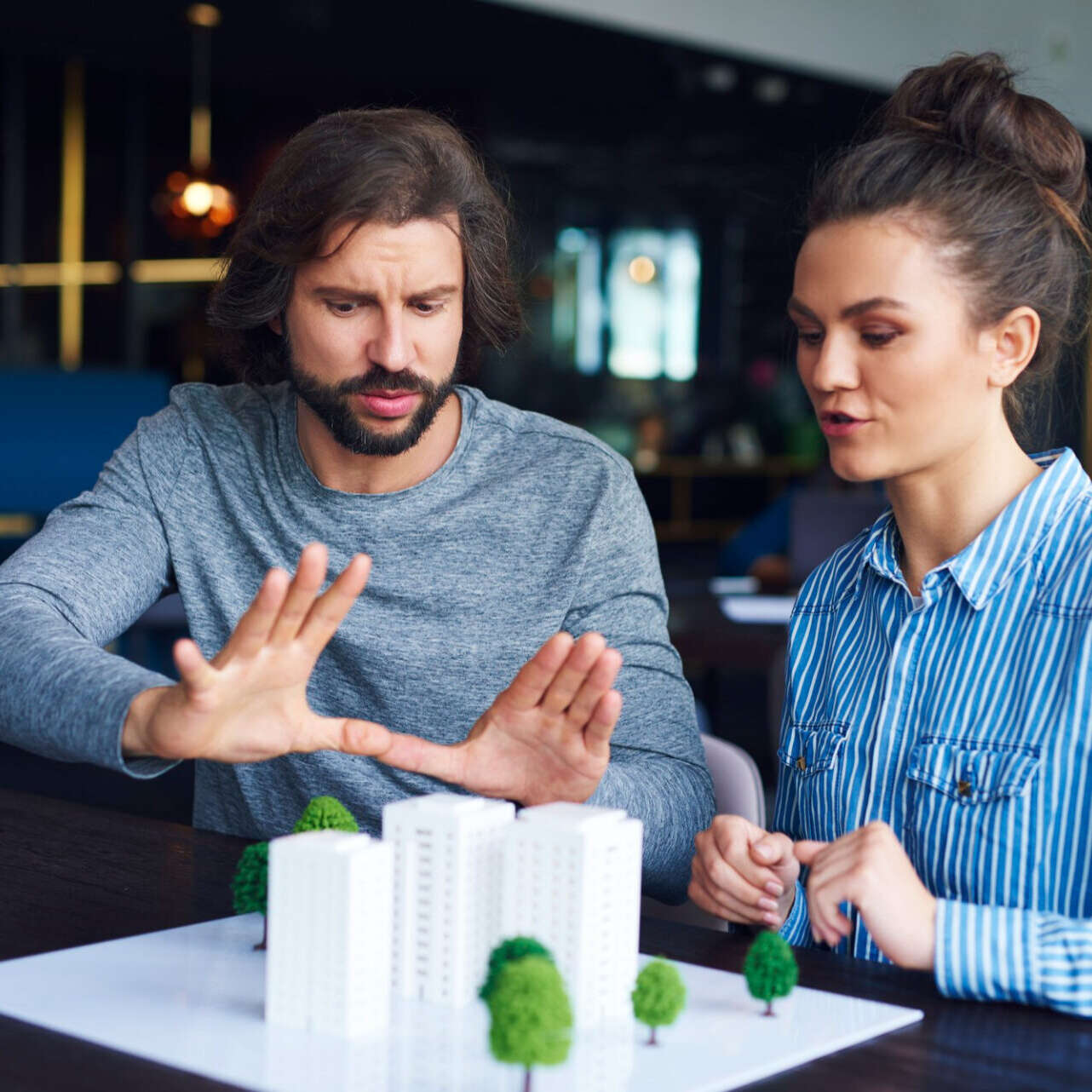 Man and woman reviewing a scale model of new apartment developments while discussing a property investment decision